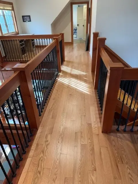 Elegant hardwood staircase with a polished surface and decorative railings, emphasizing quality and design.