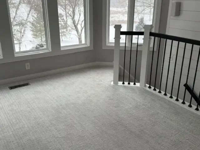 A white carpeted room featuring a black railing along the wall in Shorewood.