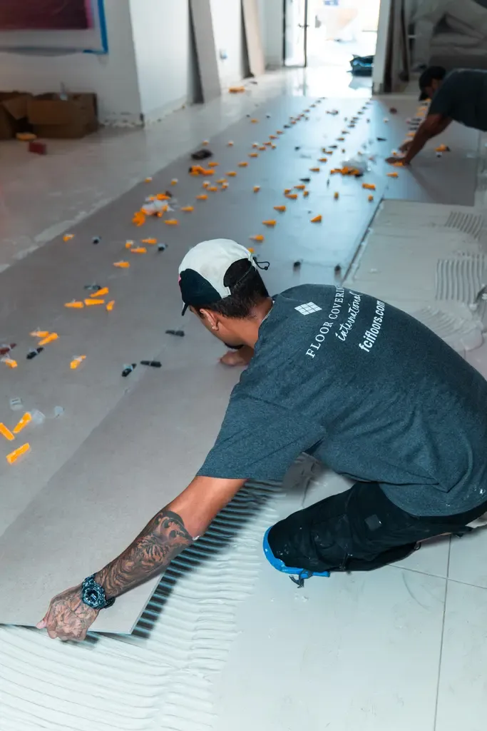 A man laying tiles on the floor in a home in Wellington, FL, focusing on precise placement and alignment.