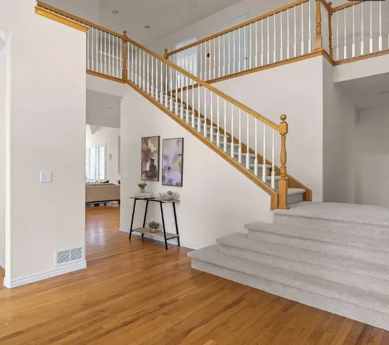 A spacious foyer featuring stairs and a white railing, showcasing fresh flooring in Aurora, CO.