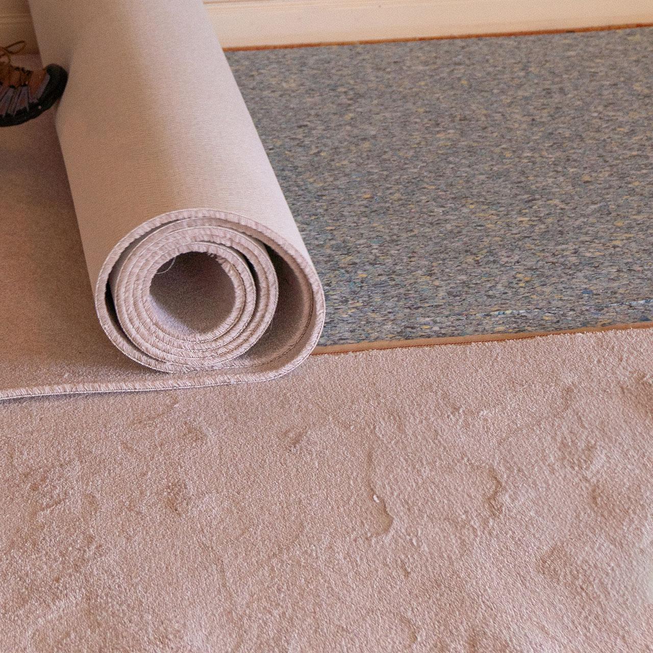A carpet roll positioned atop an existing carpet, illustrating the layered flooring concept.