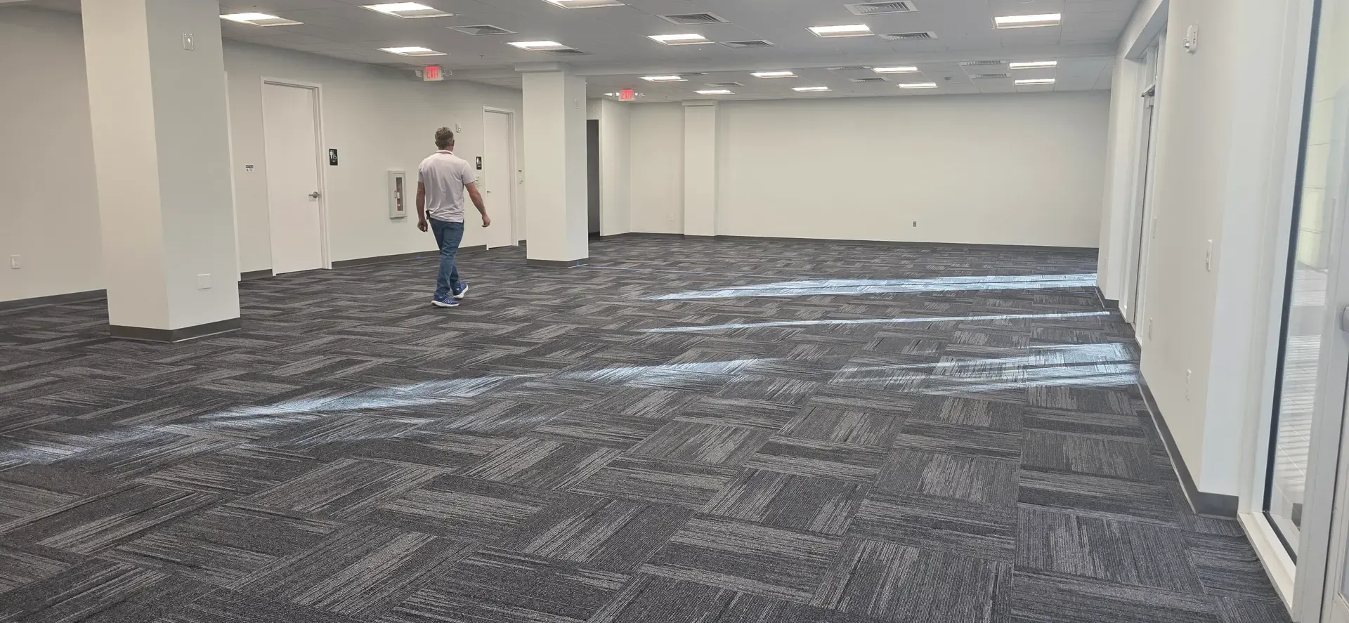  An empty office in Jupiter, FL, with a man walking on commercial carpet.