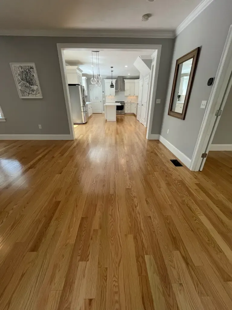 An empty living room with polished hardwood floors, located in Foxboro, MA, highlighting a minimalist and tidy design.