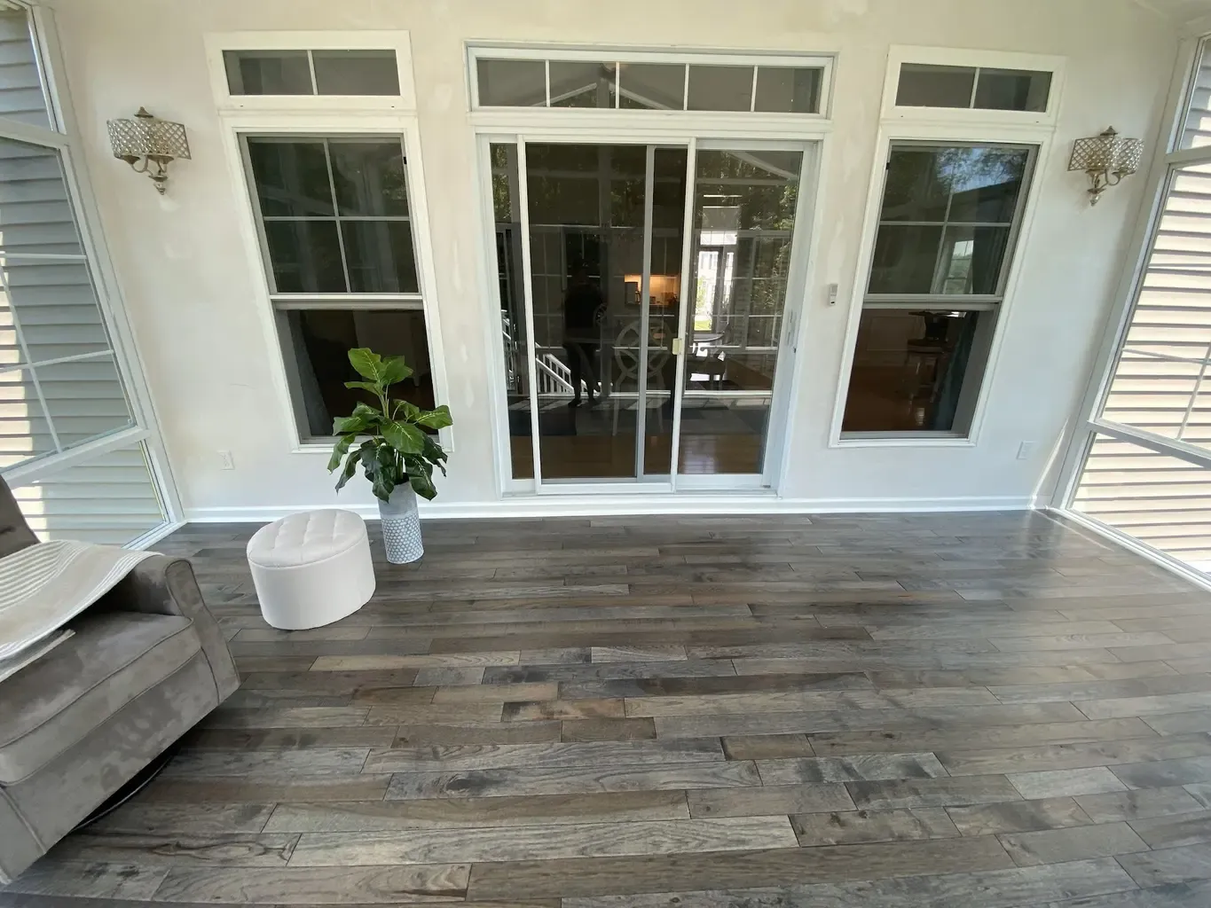 A sunroom in Foxboro, MA, featuring a couch and chairs on wood flooring, creating a cozy and inviting atmosphere.