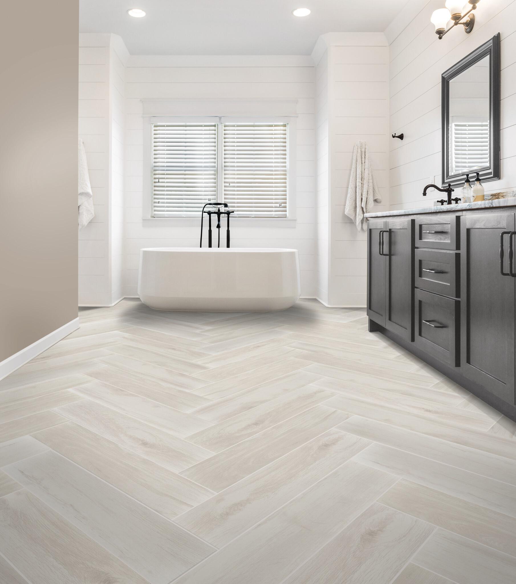 an off-white herringbone floor tile pattern leads you to a white soaking tub