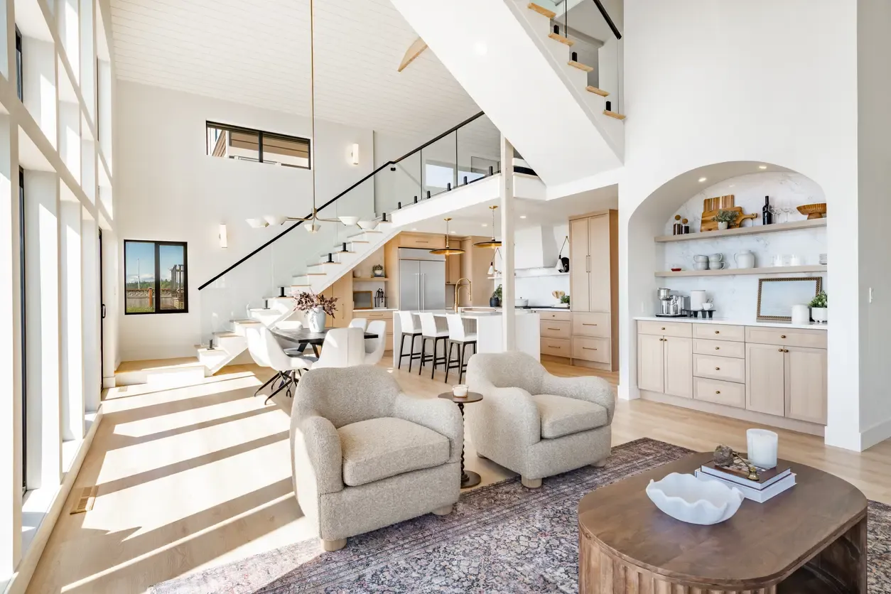  A bright living room showcasing a staircase and an adjoining kitchen, creating an inviting open concept space.