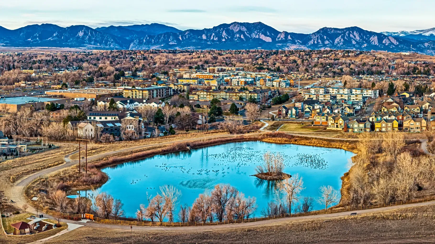 Aerial perspective of a city featuring a lake and mountains, highlighting the blend of urban and natural environments.