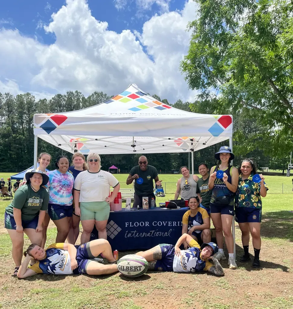 A cheerful group of women poses for a picture under a tent, showcasing camaraderie and joy.