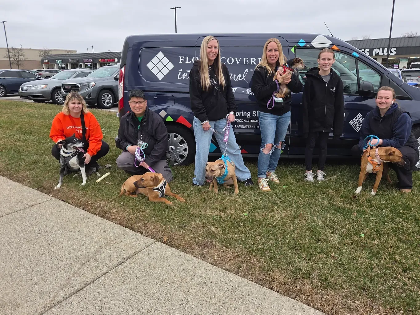 The Shelby Township team gather for a photo in front of the Mobile Flooring Showroom® van at Pet Supplies Plus Adoption Day, showcasing community spirit.