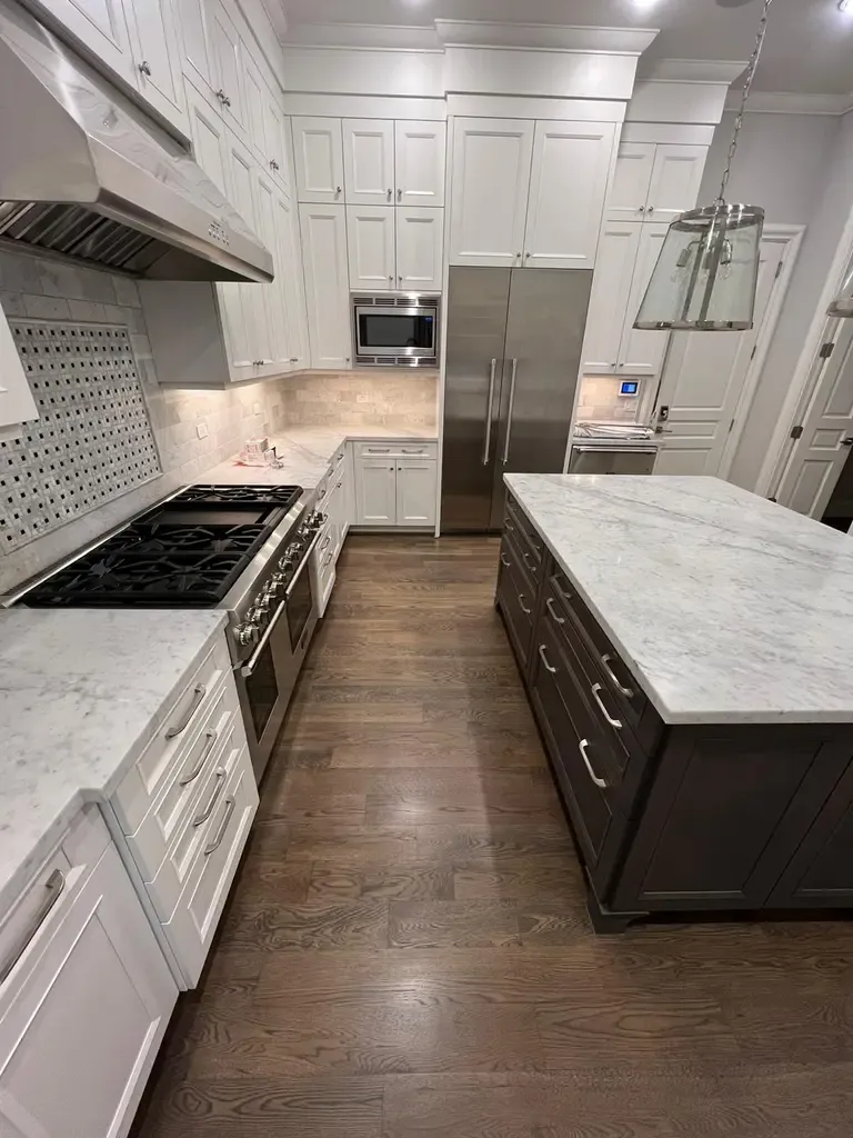 A stylish kitchen with a marble island and beautifully maintained hardwood floors, highlighting recent repair work.