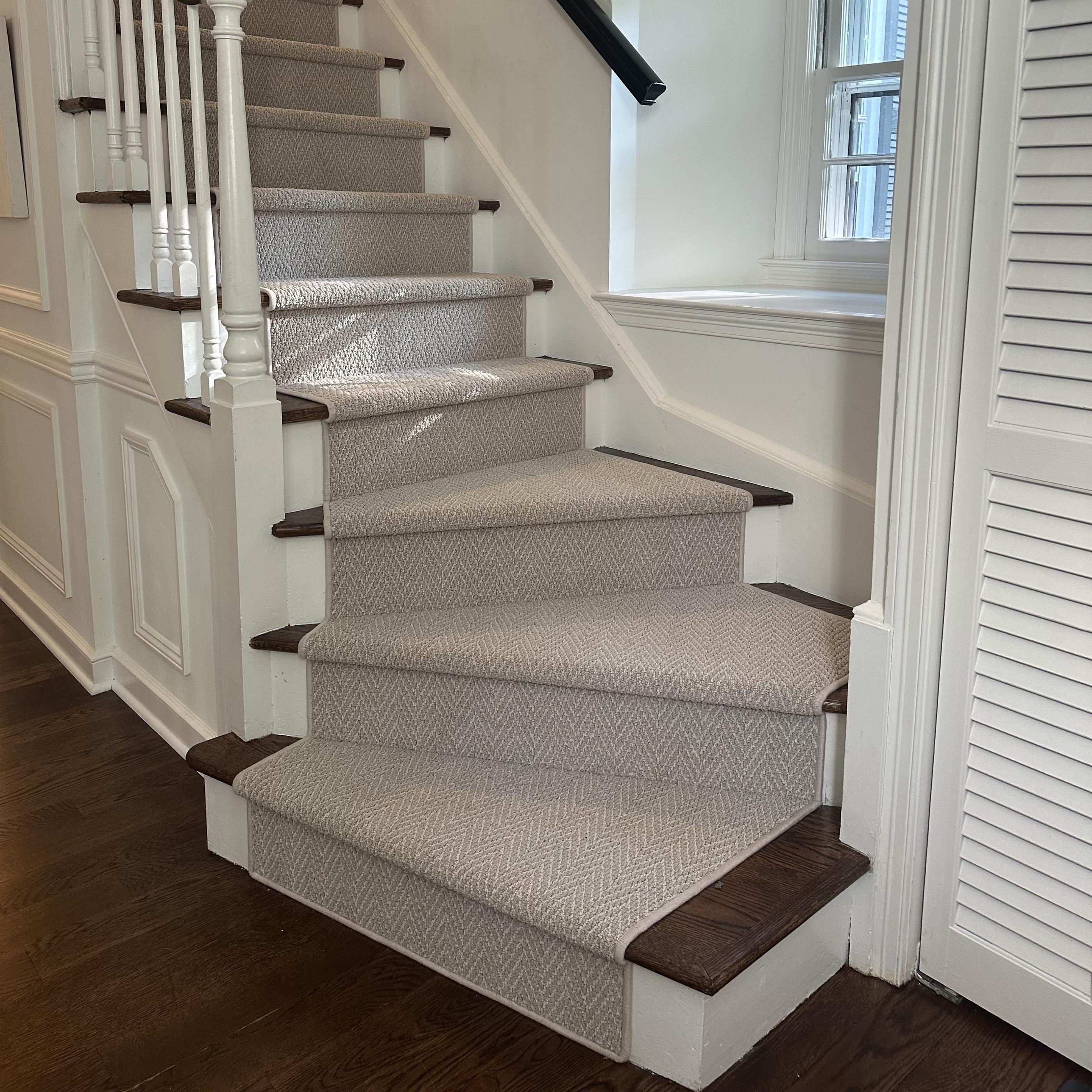 A curving staircase with hardwood treads and a beige runner.