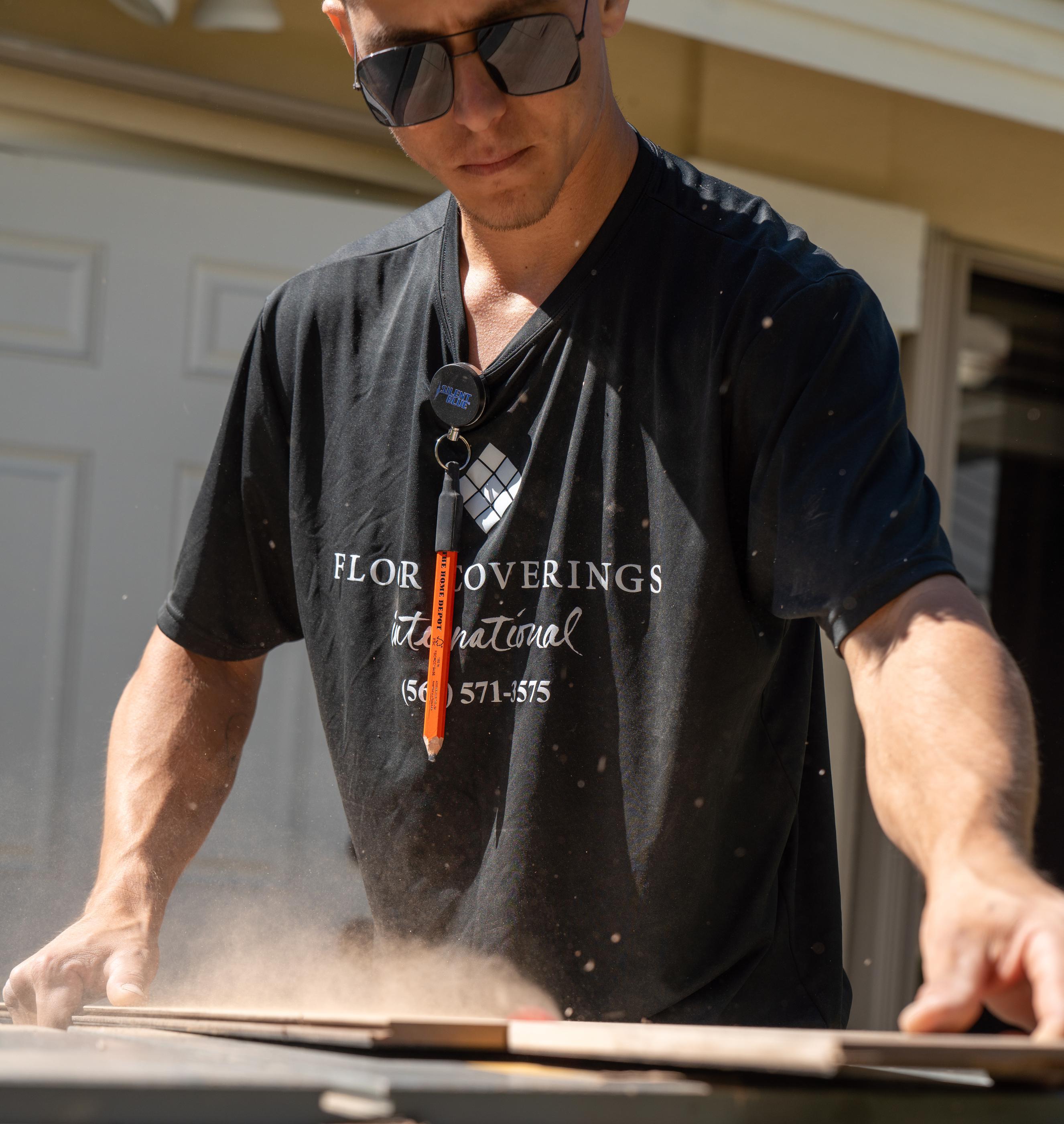 Installer cutting laminate flooring outdoors to minimize dust during installation.