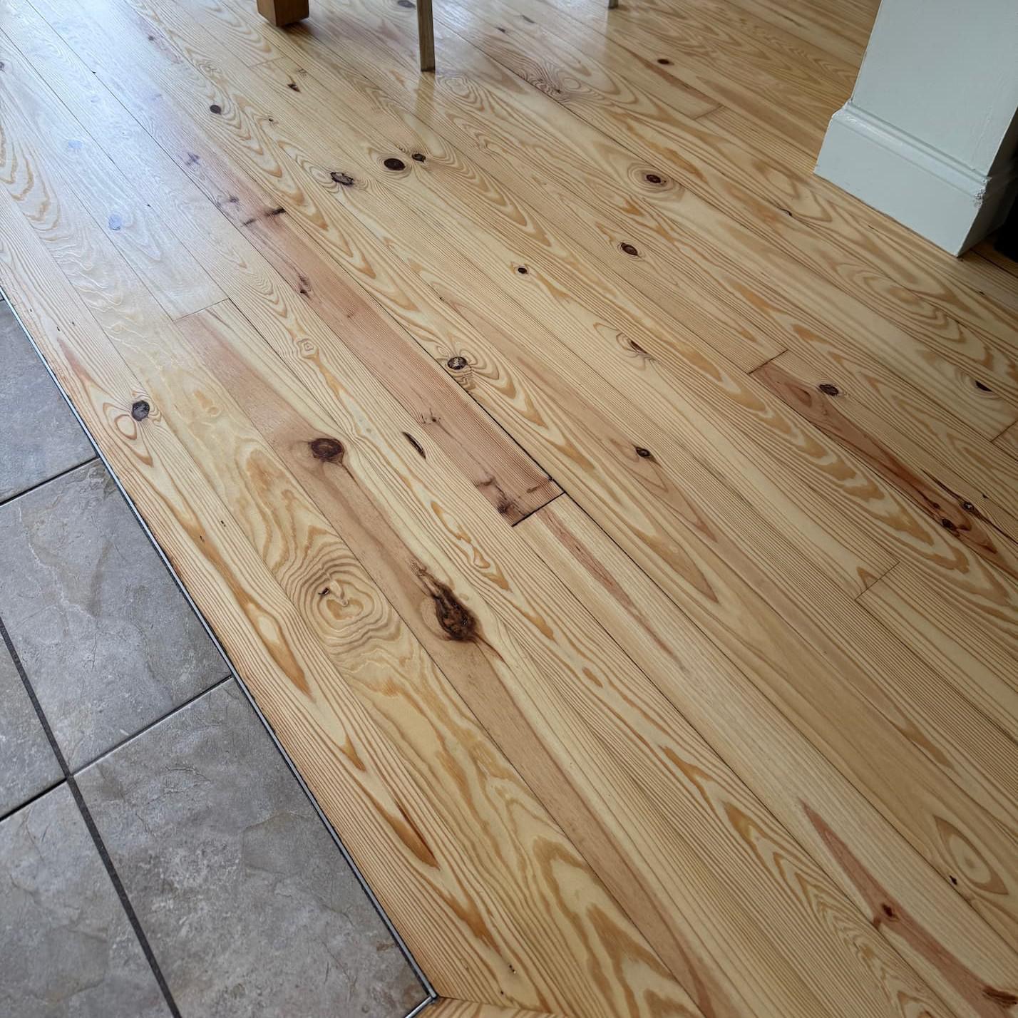 A tile floor and a hardwood floor neatly meet. 