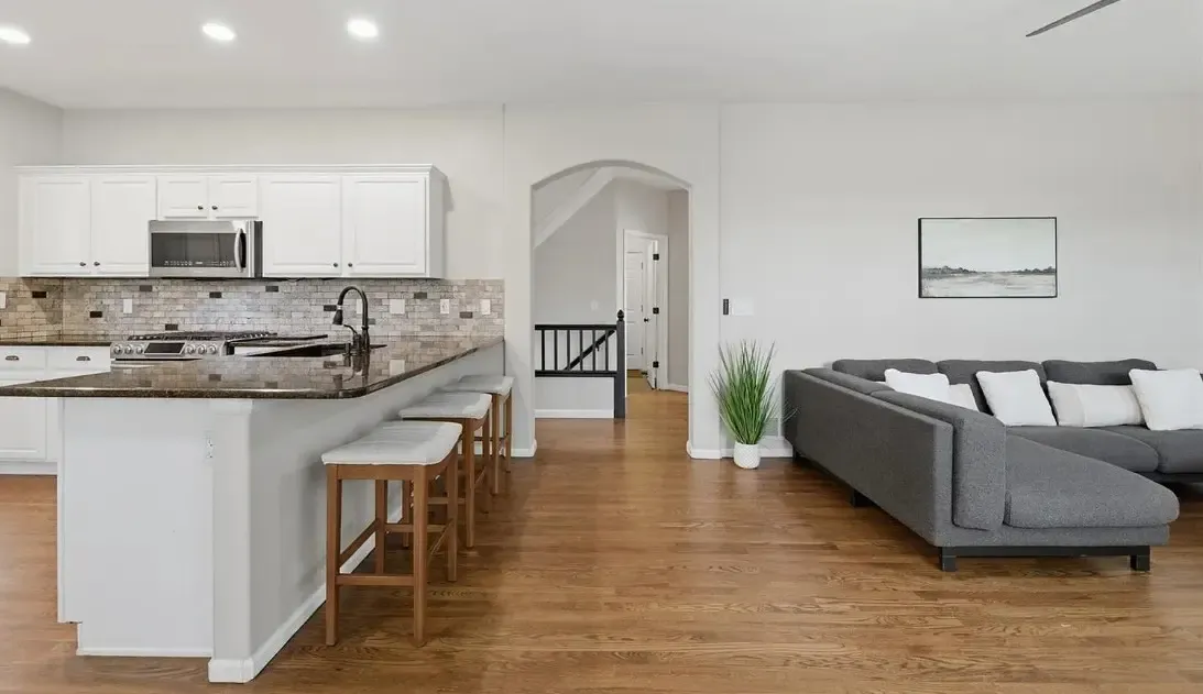 Bright kitchen and living room area with elegant hardwood flooring, emphasizing a spacious and contemporary atmosphere.