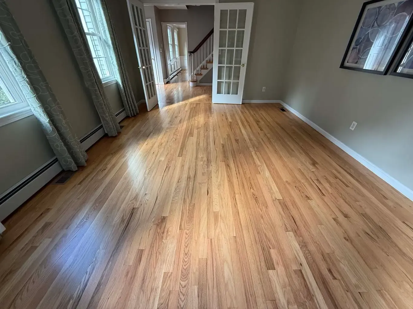 A beautifully installed natural hardwood floor in a well lit home, showcasing the warm tones and grain patterns of the wood.