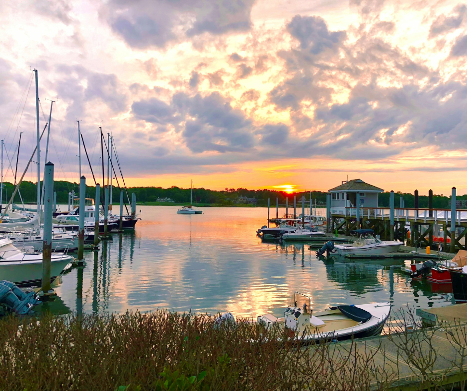 Boats tied up at the dock on the water at sunset 