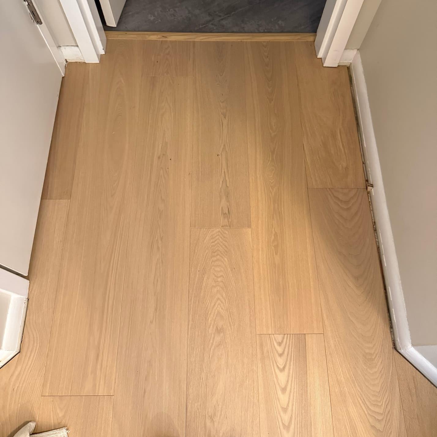 A black tile floor meets up neatly with light toned hardwood.